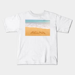 Inscription "RELAX" made on beautiful beach by the blue sea Kids T-Shirt